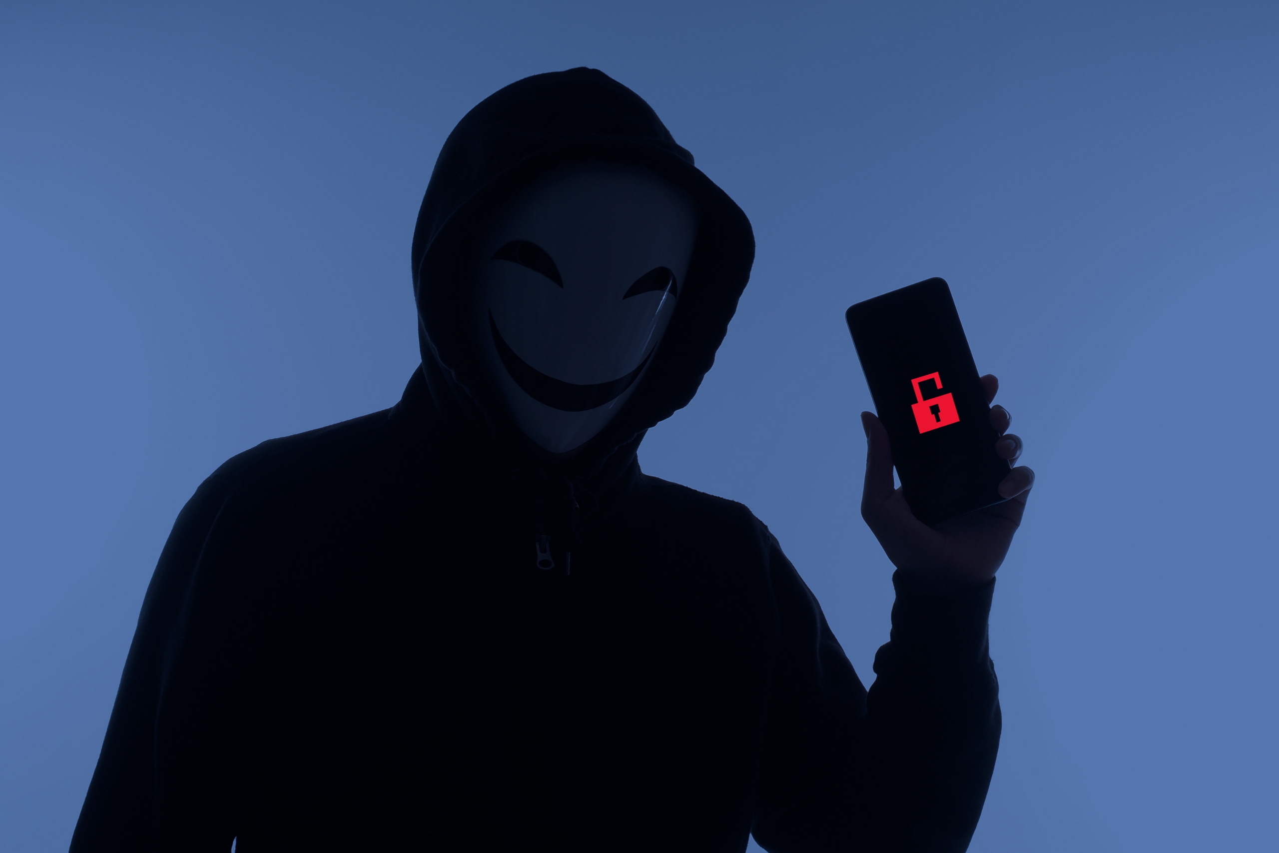 Hacker Anonymous and face mask with smartphone in hand